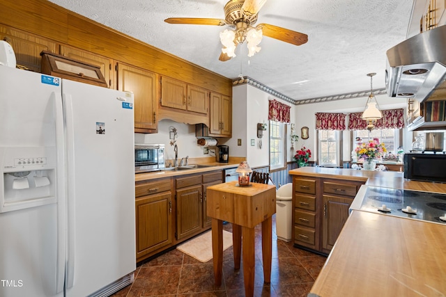 kitchen featuring ventilation hood, white refrigerator with ice dispenser, pendant lighting, and a textured ceiling