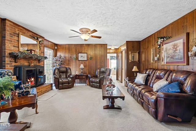 carpeted living room featuring a brick fireplace, plenty of natural light, a textured ceiling, and wood walls