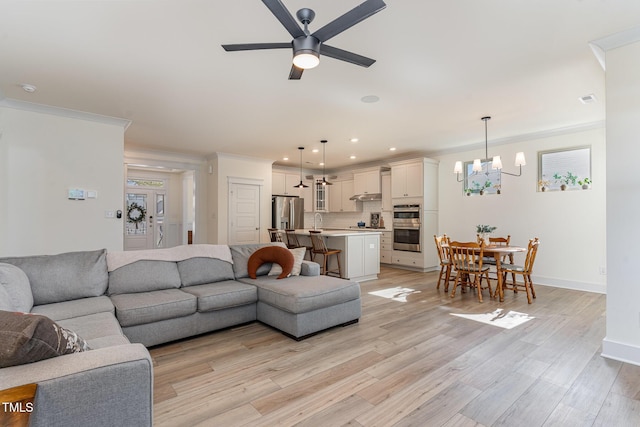 living room featuring crown molding, ceiling fan with notable chandelier, and light hardwood / wood-style flooring