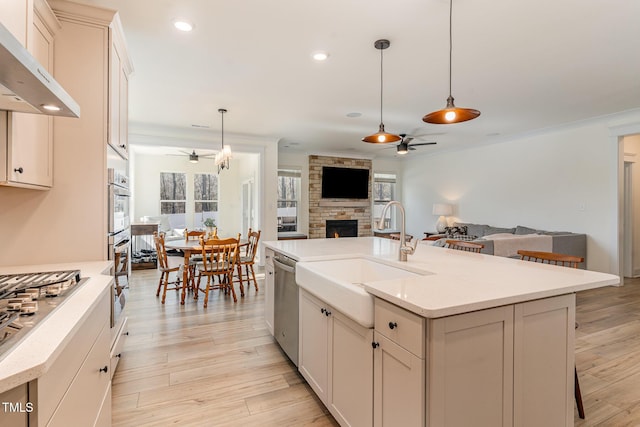 kitchen featuring a stone fireplace, a kitchen island with sink, pendant lighting, and ceiling fan