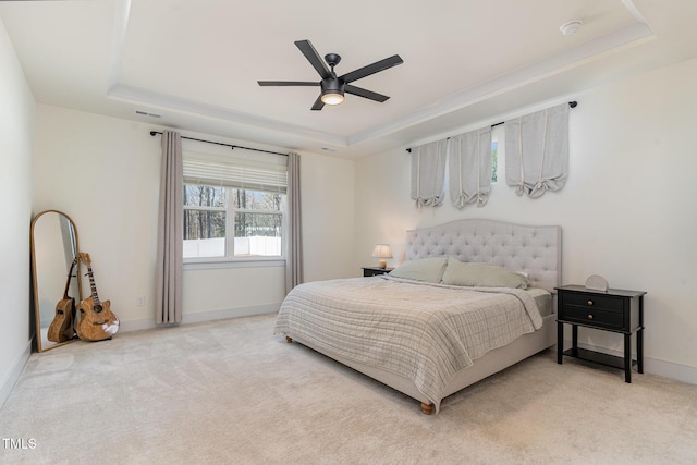 carpeted bedroom with ceiling fan and a tray ceiling