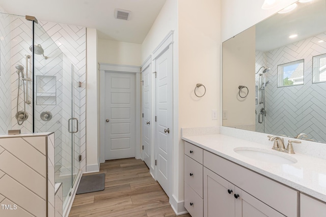 bathroom with a shower with door, vanity, and hardwood / wood-style floors