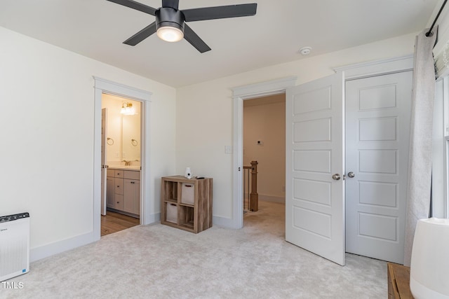 unfurnished bedroom with light carpet, sink, ensuite bath, and ceiling fan