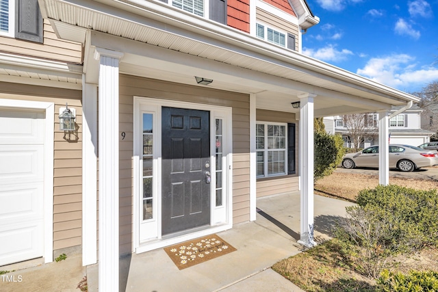 view of exterior entry with a garage and covered porch