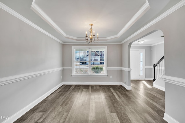 unfurnished dining area featuring ornamental molding, an inviting chandelier, dark hardwood / wood-style flooring, and a tray ceiling