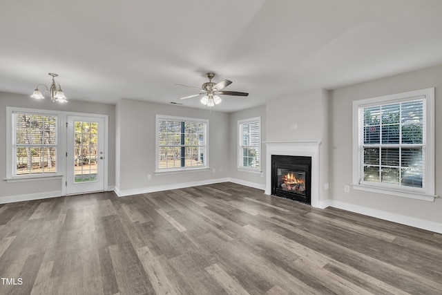 unfurnished living room featuring hardwood / wood-style floors, ceiling fan with notable chandelier, and a wealth of natural light