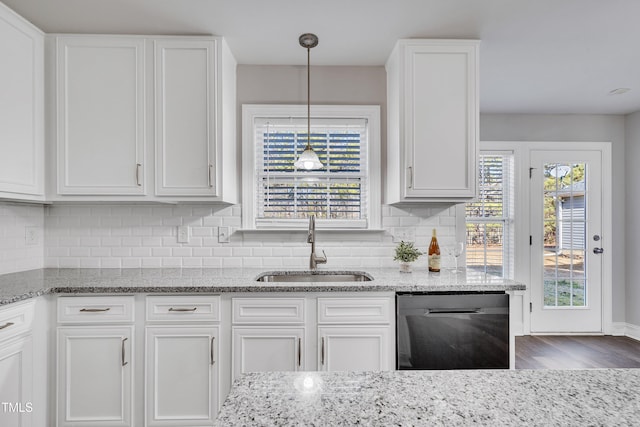 kitchen with white cabinetry, dishwasher, light stone countertops, and sink