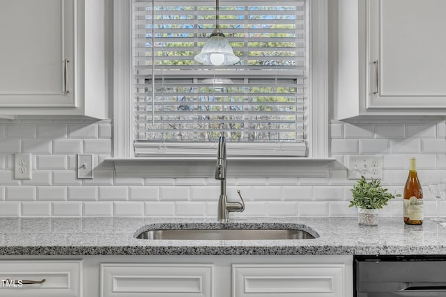 interior details featuring pendant lighting, sink, white cabinets, decorative backsplash, and light stone counters