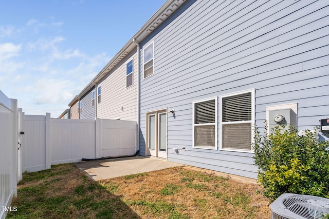 view of side of home featuring a patio area, a fenced backyard, and central AC