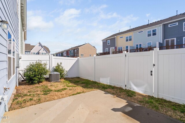 view of yard with a fenced backyard, a residential view, central AC unit, and a patio