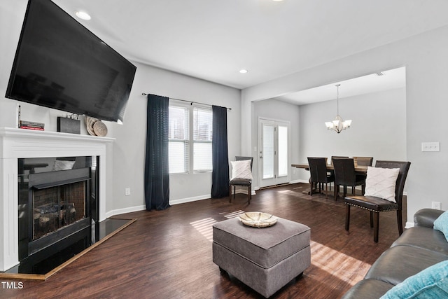 living area with baseboards, a fireplace with raised hearth, wood finished floors, a chandelier, and recessed lighting