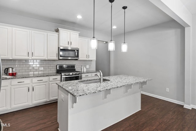 kitchen featuring stainless steel appliances, dark wood finished floors, a sink, and backsplash