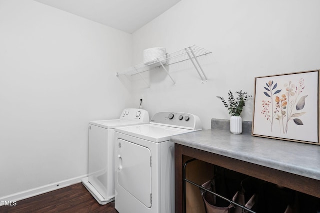 clothes washing area with laundry area, dark wood-style flooring, washing machine and clothes dryer, and baseboards