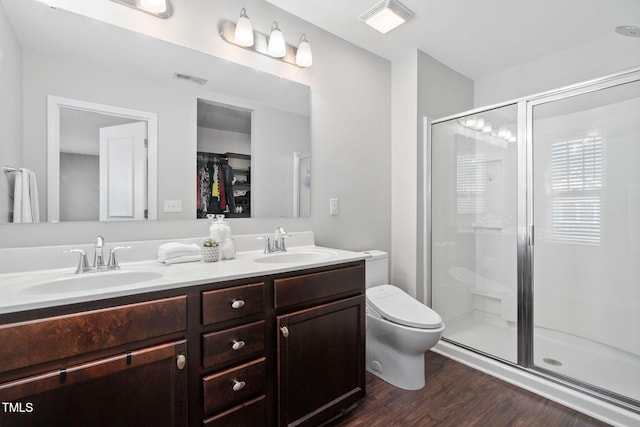 full bath with double vanity, wood finished floors, a sink, and a shower stall