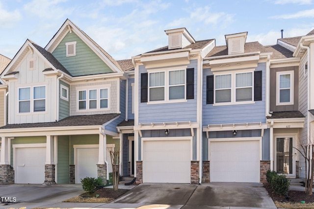 multi unit property with stone siding, board and batten siding, an attached garage, and driveway