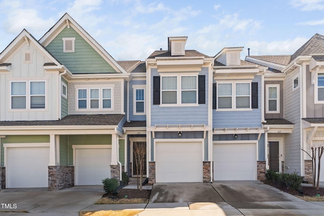 multi unit property featuring driveway, stone siding, an attached garage, and board and batten siding