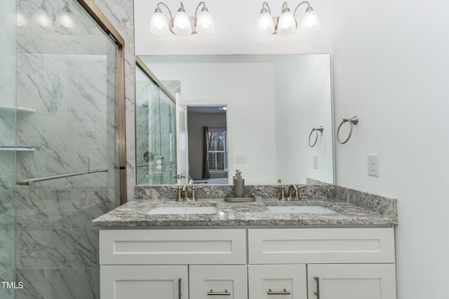 full bath with a sink, a marble finish shower, and double vanity