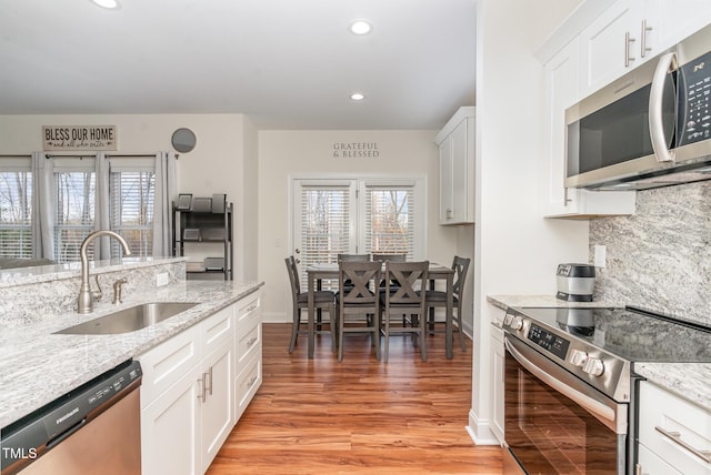 kitchen featuring white cabinetry, sink, light stone counters, and appliances with stainless steel finishes