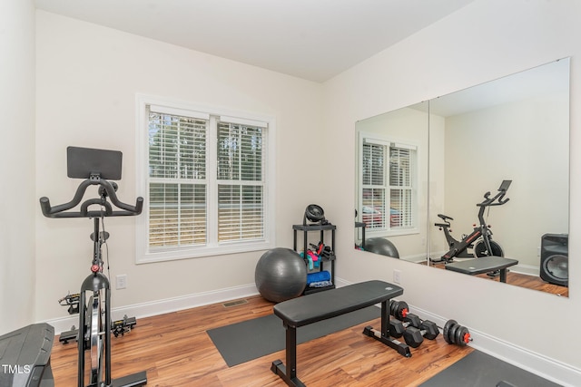 exercise area with baseboards, visible vents, and light wood-style floors