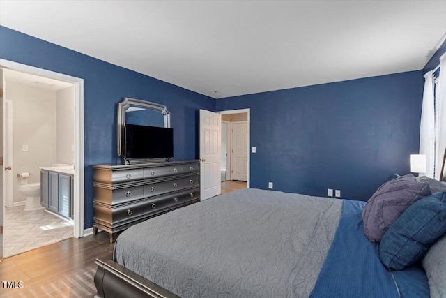 bedroom with ensuite bath and hardwood / wood-style floors