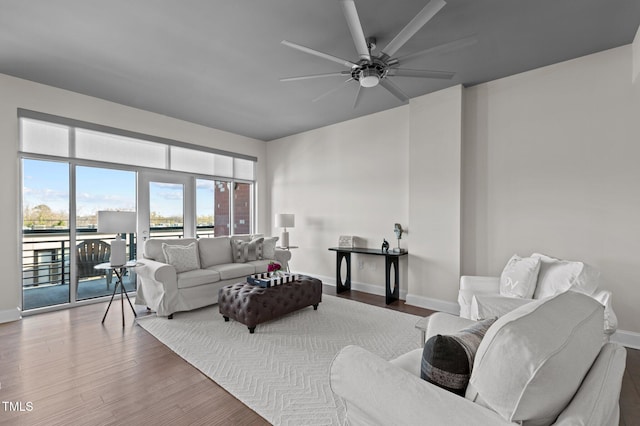 living area with baseboards, wood finished floors, and a ceiling fan