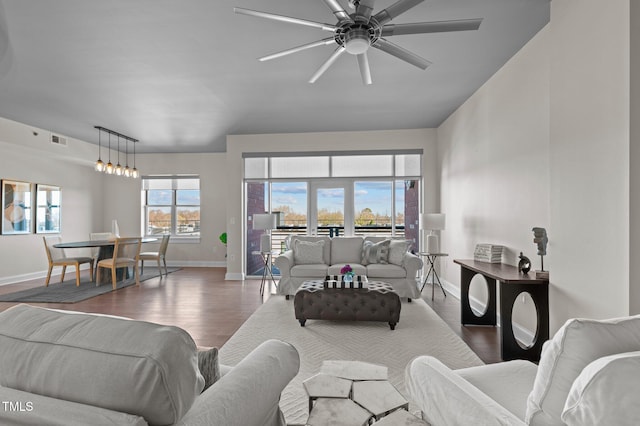 living area with visible vents, baseboards, wood finished floors, and a ceiling fan