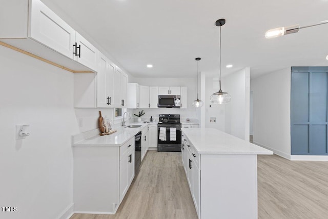 kitchen with sink, black appliances, a center island, pendant lighting, and white cabinets