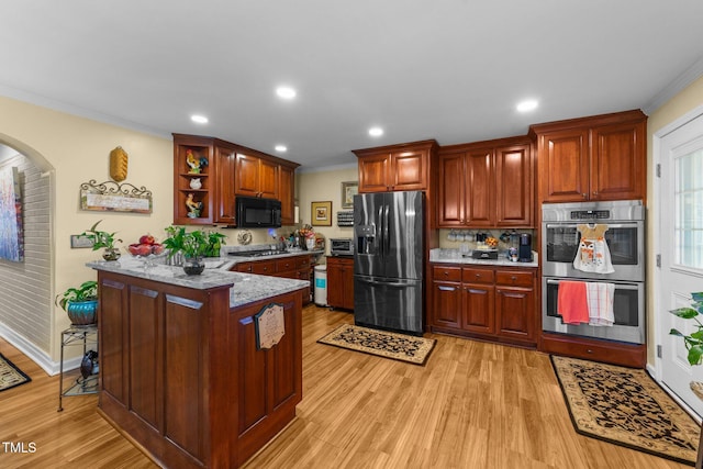 kitchen featuring a kitchen bar, ornamental molding, light stone countertops, light hardwood / wood-style floors, and black appliances