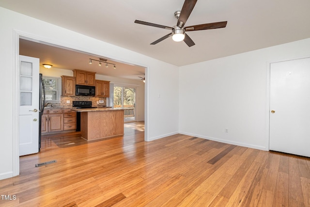 kitchen featuring tasteful backsplash, ceiling fan, light wood-type flooring, and black appliances