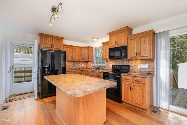 kitchen featuring backsplash, light hardwood / wood-style flooring, black appliances, and a center island