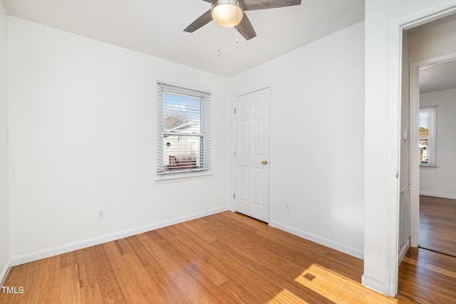 unfurnished bedroom with multiple windows, wood-type flooring, and ceiling fan