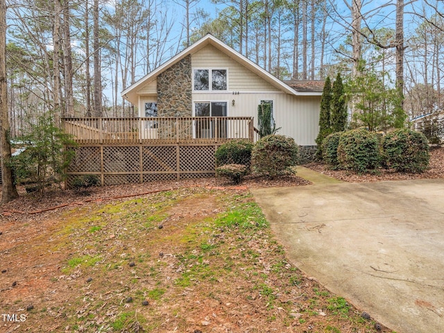 rear view of property with stone siding and a wooden deck