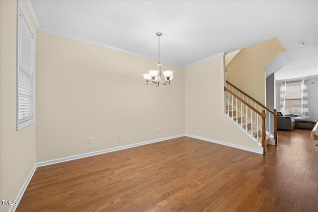 empty room with crown molding, dark hardwood / wood-style flooring, and a chandelier