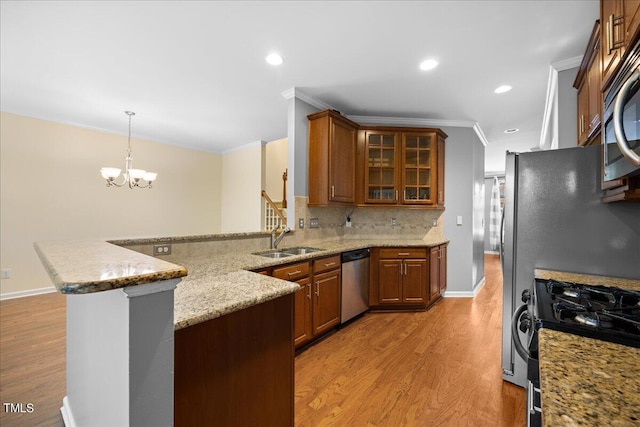 kitchen with sink, kitchen peninsula, pendant lighting, stainless steel appliances, and light hardwood / wood-style floors