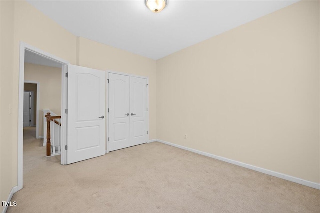 unfurnished bedroom with light carpet and a closet