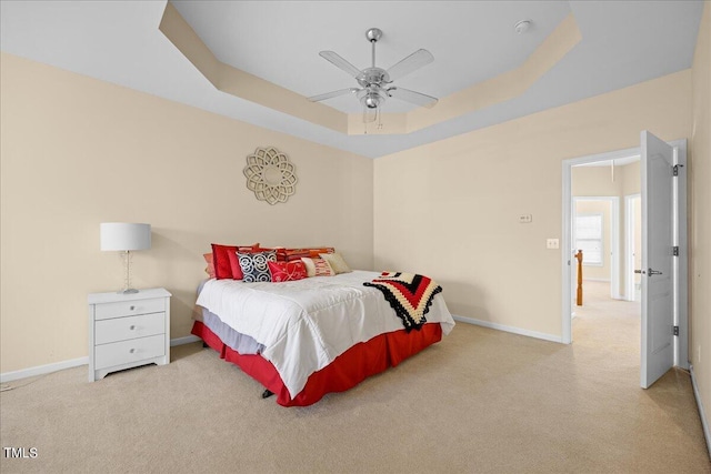 carpeted bedroom featuring a raised ceiling and ceiling fan