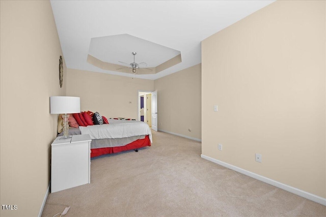 carpeted bedroom with ceiling fan and a tray ceiling