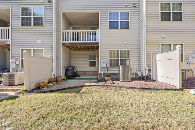 back of house with central AC unit and a lawn