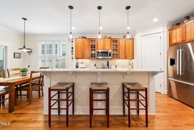 kitchen featuring a breakfast bar area, a kitchen island, stainless steel appliances, light stone countertops, and decorative backsplash