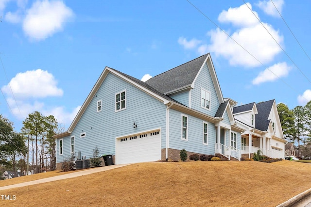 view of front of house with a garage, a porch, a front yard, and cooling unit