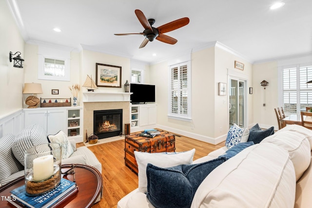 living room with ornamental molding, ceiling fan, and light hardwood / wood-style floors