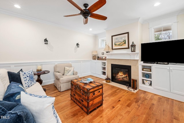 living room with crown molding, ceiling fan, and light hardwood / wood-style flooring