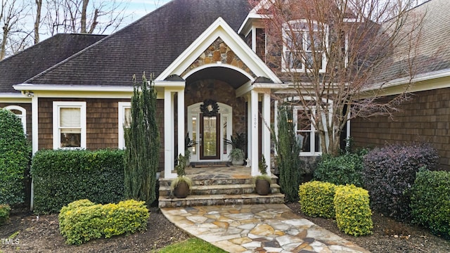 property entrance with stone siding and a shingled roof