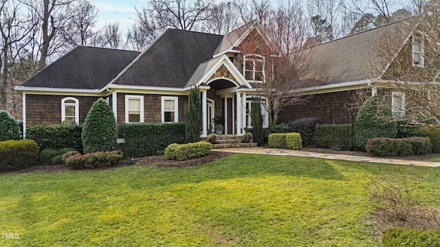 view of front facade featuring a shingled roof and a front yard