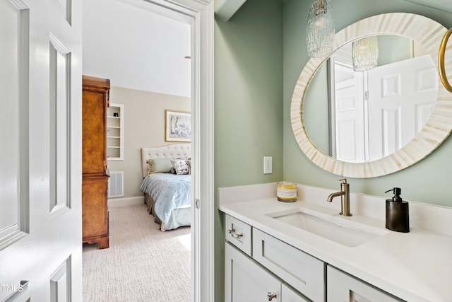 bathroom with baseboards, visible vents, vanity, and ensuite bath