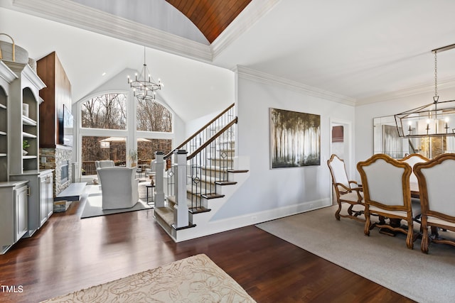 foyer featuring a chandelier, dark wood finished floors, crown molding, and stairway