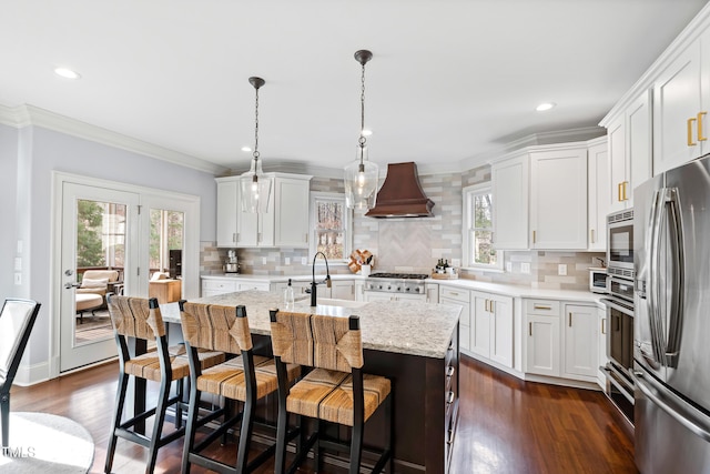 kitchen featuring dark wood-style floors, ornamental molding, stainless steel appliances, premium range hood, and a sink