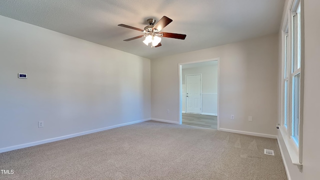 empty room with a textured ceiling, light colored carpet, and ceiling fan