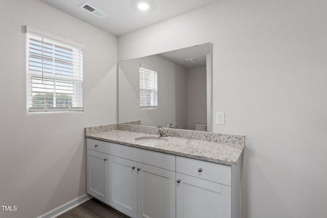 half bathroom featuring baseboards, vanity, toilet, and wood finished floors