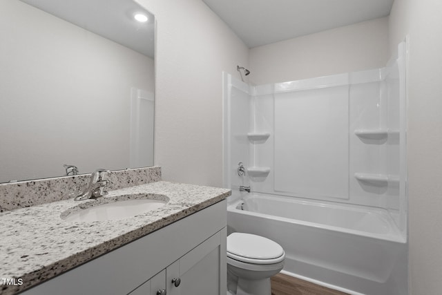 bathroom featuring toilet, wood finished floors, vanity, and bathtub / shower combination